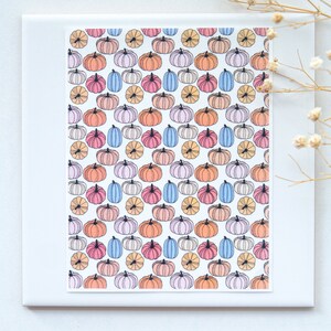 May include: A white background with a repeating pattern of colorful pumpkins. The pumpkins are in shades of orange, pink, blue, and yellow. The pumpkins are outlined in black and have a simple, hand-drawn style.