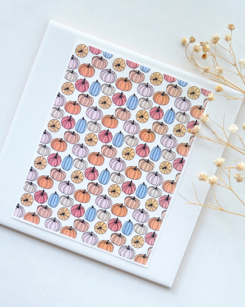 May include: A white background with a colorful pattern of pumpkins. The pumpkins are in shades of pink, orange, blue, and yellow. The pumpkins are all different sizes and shapes.