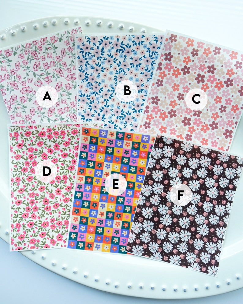May include: Six different floral patterned sheets of paper, labelled A through F. The patterns include pink flowers on a white background, blue flowers on a white background, pink flowers on a beige background, pink flowers on a green background, colourful flowers in a checkered pattern, and white flowers on a brown background.
