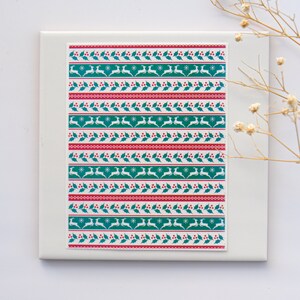 May include: A sheet of Christmas themed washi tape with a repeating pattern of green holly leaves, red berries, white snowflakes, and white reindeer.