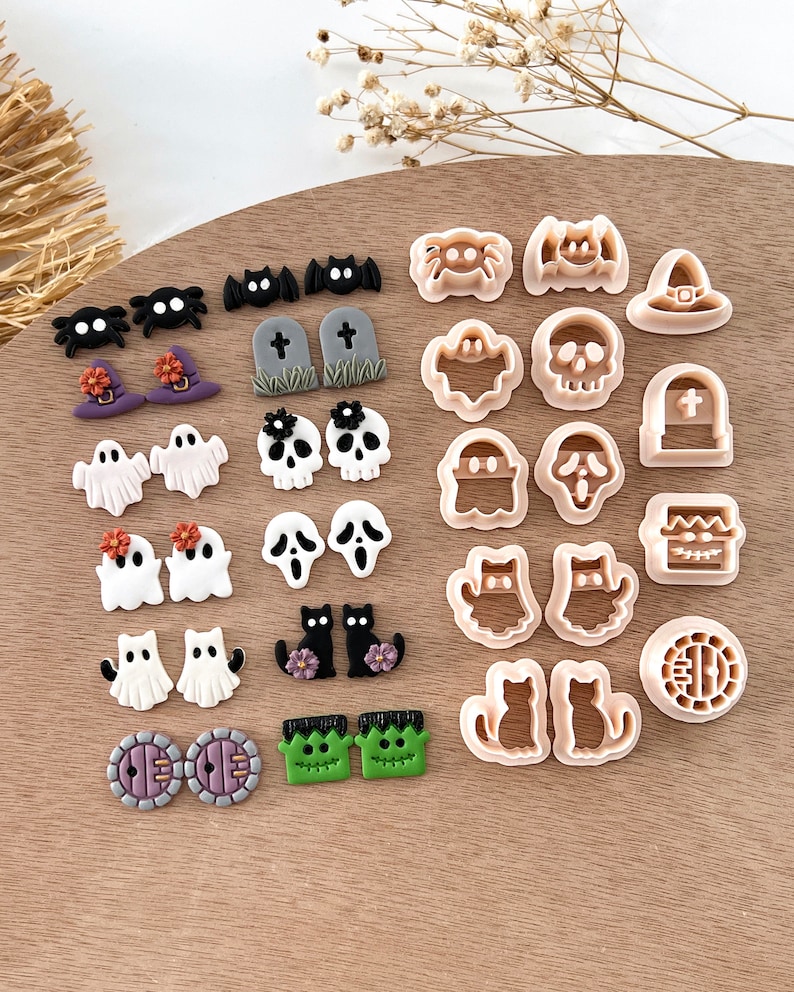Pu&ograve; includere: Un set di 20 tagliabiscotti a tema Halloween, tra cui fantasmi, pipistrelli, ragni, gatti, zucche e altro ancora. I tagliabiscotti sono in plastica beige chiaro e sono disposti su una superficie di legno.