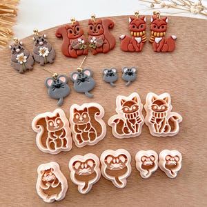 May include: A set of 10 polymer clay earrings and cookie cutters featuring foxes, squirrels, and mice. The earrings are brown, gray, and orange. The cookie cutters are white.