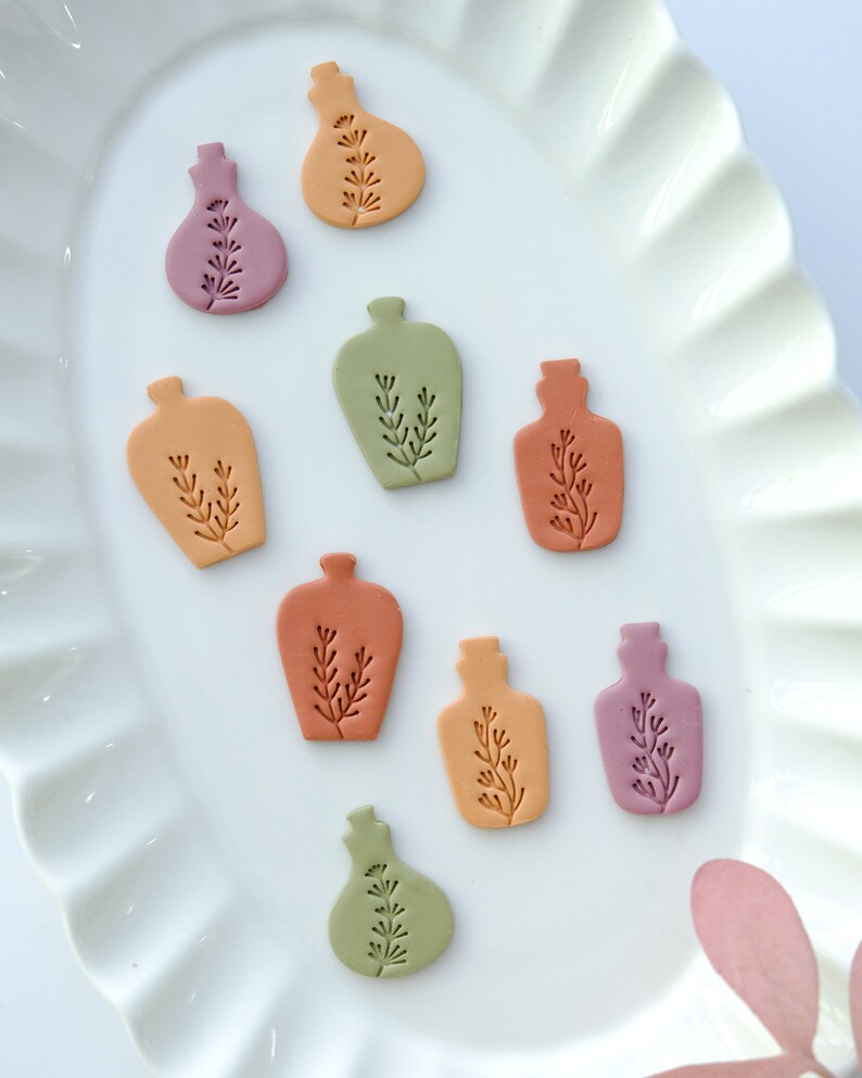 May include: Nine small ceramic bottles in various shades of orange, pink, and green. Each bottle has a simple floral design.
