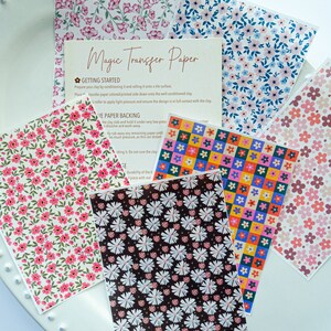 May include: A set of six sheets of floral patterned transfer paper for use with clay. The paper features a variety of floral designs, including pink flowers, white flowers, and colourful squares. The paper is labelled "Magic Transfer Paper" and includes instructions for use.