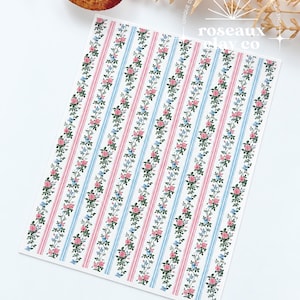 May include: A rectangular silk screen sheet featuring a repeating vertical pattern of pink rose vines and blue forget-me-nots alternating with thin pink and blue stripes on a white background. The text roseaux clay co is printed in white.