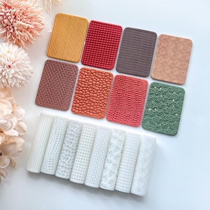 Könnte beinhalten: Eine Sammlung von strukturierten rechteckigen und zylindrischen Formen in verschiedenen Farben. Die rechteckigen Formen weisen Muster wie Streifen, Webstrukturen und geometrische Designs auf. Die zylindrischen Formen haben vertikale Linien, Ziegel und florale Muster.