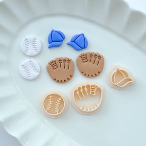 Pu&ograve; includere: Un set di nove topper e tagliapasta in pasta di zucchero a tema baseball. I topper includono due palline da baseball bianche, due guanti da baseball marroni e due cappellini da baseball blu. I tagliapasta includono una pallina da baseball bianca, un guanto da baseball marrone e un cappellino da baseball blu.