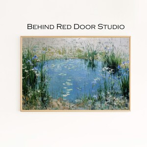 Op de afbeelding: Een ingelijst schilderij van een vijver met blauwe waterlelies en blauwe irissen. Hoge groene riet- en grassoorten omringen de vijver. De tekst "BEHIND RED DOOR STUDIO" staat boven het schilderij.
