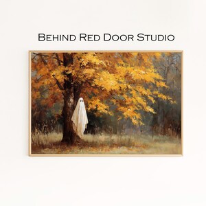 Puede incluir: Una impresión artística enmarcada que presenta un fantasma colgado de un árbol en un bosque. El árbol tiene hojas amarillas y naranjas. El texto "BEHIND RED DOOR STUDIO" está en la parte superior de la imagen.