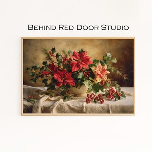 Könnte beinhalten: Gerahmtes Blumenstillleben mit einer cremefarbenen Vase, die mit roten Weihnachtssternen, Stechpalmen und Beeren überfüllt ist. Das Kunstwerk ist vor einem neutralen Hintergrund und drapiertem Stoff platziert. Der Text "BEHIND RED DOOR STUDIO" steht oben.