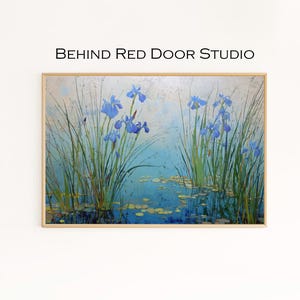 Op de afbeelding: Een ingelijst schilderij met blauwe irissen en lange groene rietstengels in een vijver. Het kunstwerk heeft een lichtblauwe en witte achtergrond, met de tekst "BEHIND RED DOOR STUDIO" bovenaan. De lijst is licht van kleur.