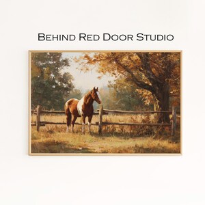 May include: A framed painting depicting a brown and white horse in a field beside a wooden fence. The artwork uses warm autumnal colours. The text "BEHIND RED DOOR STUDIO" is displayed at the top of the image.