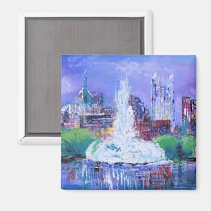Könnte beinhalten: Ein quadratischer Magnet mit einem impressionistischen Gemälde einer Stadtlandschaft, einschließlich eines Brunnens. Das Kunstwerk verwendet Blau-, Lila-, Grün- und Rottöne. Der Magnet ist in einen weißen Rahmen und eine graue Magnetrückseite gefasst.