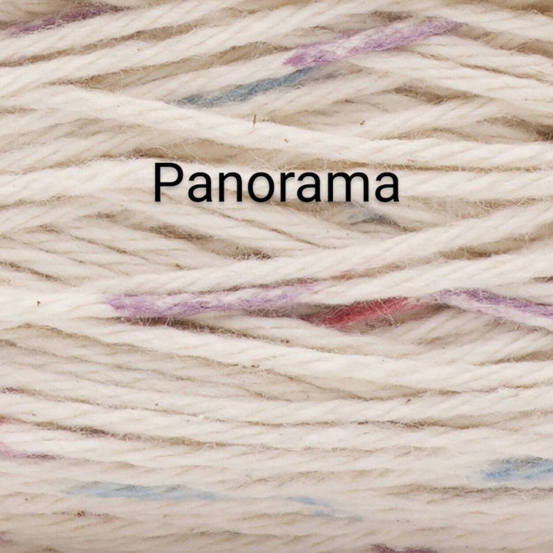 Puede incluir: Primer plano de un ovillo de lana color crema con motas moradas, azules y rojas. La palabra "Panorama" est&aacute; impresa en negro sobre la lana. Ideal para proyectos de punto y ganchillo.