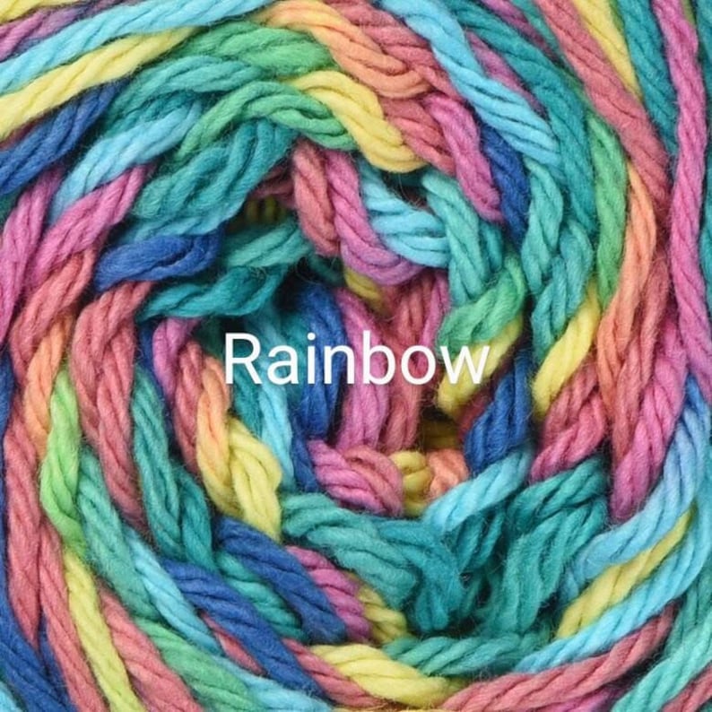 Puede incluir: Primer plano de un ovillo de hilo colorido. El hilo es una mezcla de colores del arco&iacute;ris, incluyendo rosa, amarillo, azul, verde y turquesa. La palabra "Rainbow" est&aacute; impresa en blanco sobre el hilo.
