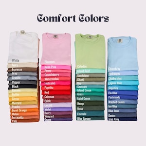 May include: A color chart of t-shirt colors with the brand name "Comfort Colors" at the top. The colors are arranged in columns, with each column representing a different color family. The colors include white, ivory, espresso, gray, granite, pepper, black, banana, butter, citrus, mustard, peachy, burnt orange, melon, terracotta, yam, blossom, neon pink, peony, crunchberry, watermelon, heliconia, paprika, red, crimson, brick, orchid, violet, berry, vineyard, grape, celedon, island reef, sandstone, khaki, bay, seafoam, island green, grass, light green, hemp, moss, emerald, blue spruce, chambray, hydrangea, chalky mint, lagoon blue, sapphire, flo blue, periwinkle, washed denim, ice blue, blue jean, denim, true navy.