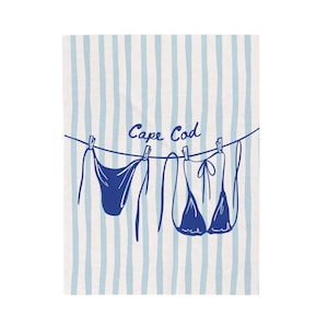 Puede incluir: Impresión a rayas azules y blancas con dos bikinis azules colgados de una cuerda con pinzas. Las palabras "Cape Cod" están escritas en azul sobre los bikinis.