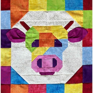 Könnte beinhalten: Ein farbenfroher Quiltblock mit einem Kuhgesicht. Das Gesicht der Kuh besteht aus geometrischen Formen in verschiedenen Farben, darunter Lila, Grün, Orange und Gelb. Der Hintergrund ist ein Patchwork aus regenbogenfarbenen Quadraten.