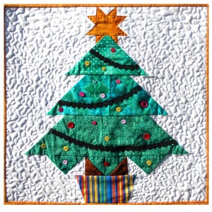 May include: A festive Christmas tree quilt with a white background. The green tree features black trim and colourful button decorations. A gold star sits at the top, and the pot is striped with multiple colours. The quilt has a textured, wavy pattern.