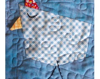 May include: A blue and white gingham patchwork quilt block with a blue bird applique. The bird has a red, white, and pink hat and a yellow beak. The quilt block is quilted with a pattern of small circles.