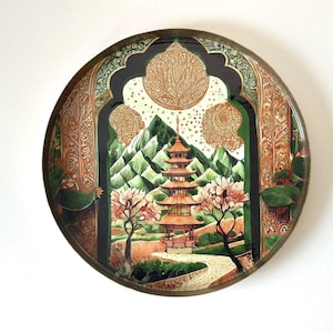 Może przedstawiać: Okrągła dekoracyjna taca z szczegółową sceną krajobrazu inspirowaną Azją. Taca przedstawia pagodę, góry, drzewa i krętą ścieżkę, obramowaną ozdobnymi łukami i metalową obwódką. Paleta kolorów obejmuje odcienie zieleni, brązu i pomarańczy.
