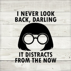 May include: Black and white graphic on a wooden background. The image features a silhouette of a woman with round glasses and the quote, "I NEVER LOOK BACK, DARLING IT DISTRACTS FROM THE NOW."