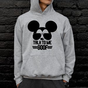May include: A gray hooded sweatshirt featuring a black graphic of Mickey Mouse wearing sunglasses. Below the graphic, the text reads "TALK TO ME GOOF" in black. The sweatshirt has a front pocket and a drawstring hood.