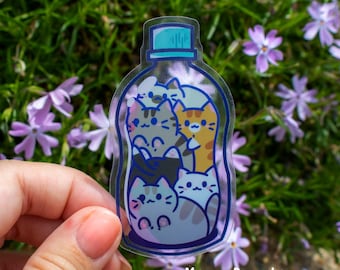 May include: A clear plastic sticker with a blue lid and a design of five cats inside a bottle. The sticker has the text "Meow Royale" at the bottom.