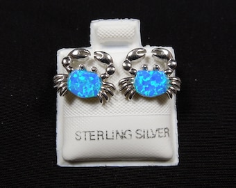 Könnte beinhalten: Ein Paar Ohrringe aus Sterlingsilber mit einem blauen Opal-Krabben-Design. Die Ohrringe werden auf einer weißen Karte mit dem Aufdruck "Sterling Silver" präsentiert.