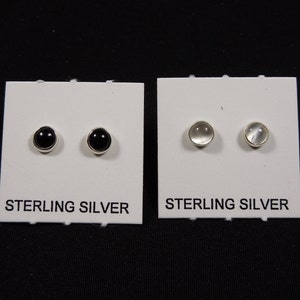 May include: Two pairs of sterling silver stud earrings. One pair features black round stones, and the other pair features clear round stones.