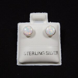 May include: A pair of white opal stud earrings on a white card with the text "STERLING SILVER".