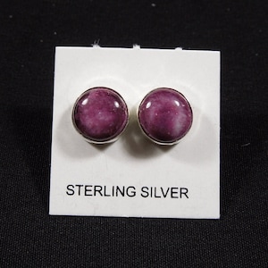 May include: A pair of sterling silver stud earrings with pink and white swirl designs. The earrings are on a white card with the text "STERLING SILVER".