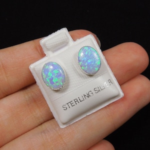 Könnte beinhalten: Ein Paar Ohrringe aus Sterlingsilber mit ovalen Opal-Steinen. Die Opale sind hellblau mit grünen und weißen Flecken.