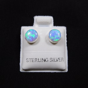 May include: A pair of sterling silver stud earrings with round blue opal stones.