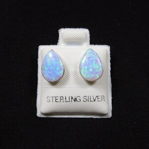Peut inclure: Une paire de boucles d'oreilles en forme de poire en opale, serties d'argent sterling. Les opales présentent un mélange de teintes bleues et vertes. Les boucles d'oreilles sont présentées sur une carte blanche avec l'inscription "STERLING SILVER".