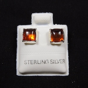 May include: A pair of sterling silver earrings with square amber stones.