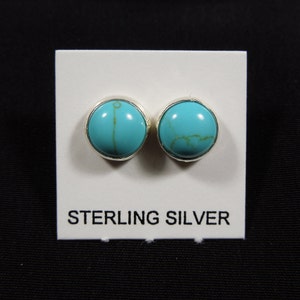 May include: A pair of sterling silver earrings with turquoise stones. The earrings are round and have a smooth finish.