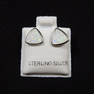 Könnte beinhalten: Ein Paar Ohrringe aus Sterlingsilber mit weißen Opal-Steinen in Dreiecksform. Die Ohrringe werden auf einer weißen Karte mit dem Aufdruck "Sterling Silver" präsentiert.