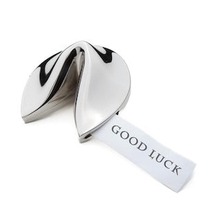 Pu&ograve; includere: Un biscotto della fortuna argentato con un foglietto di carta bianco che dice "GOOD LUCK".
