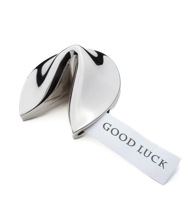 Pu&ograve; includere: Un biscotto della fortuna argentato con un foglietto di carta bianco che dice "GOOD LUCK".