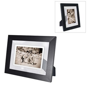 May include: Black picture frame with a silver mat and a photo of two boys on a beach. The frame has a stand on the back.