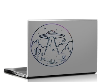 Adesivo para laptop com tema de abdução alienígena por OVNI no deserto, ficção científica retrô.
