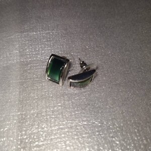 May include: A pair of silver earrings with green rectangular stones.