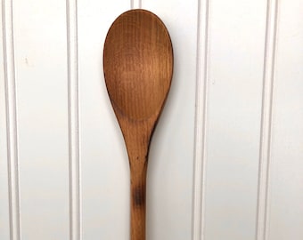 May include: A wooden spoon with a brown finish. The spoon is long and has a rounded head.