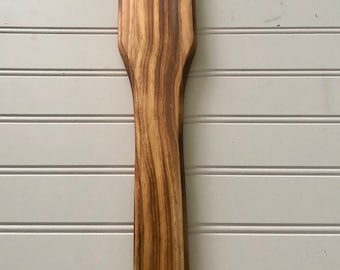 May include: A wooden spatula with a dark brown stain and a natural wood grain pattern.