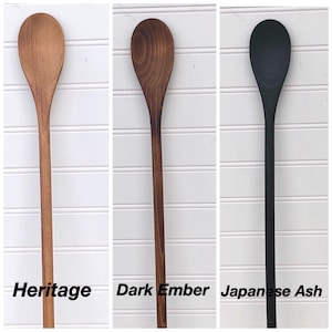 May include: Three wooden spoons, one in a natural wood finish labelled "Heritage", one in a dark brown finish labelled "Dark Ember", and one in a black finish labelled "Japanese Ash".
