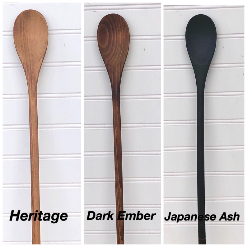 May include: Three wooden spoons, one in a natural wood finish labelled "Heritage", one in a dark brown finish labelled "Dark Ember", and one in a black finish labelled "Japanese Ash".