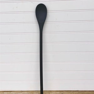 May include: A long, black wooden spoon with a rounded head.