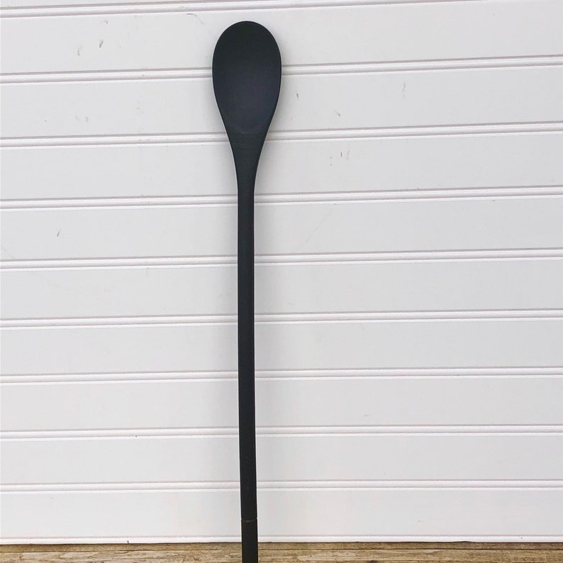 May include: A long, black wooden spoon with a rounded head.