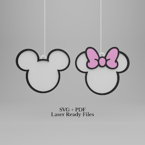 Könnte beinhalten: Zwei hängende mausförmige Umrisse mit schwarzen Rändern und weißen Zentren. Ein Umriss ist schlicht, während der andere eine rosa Schleife aufweist. Der Text SVG + PDF Laser Ready Files ist unter den Formen auf hellgrauem Grund zentriert.